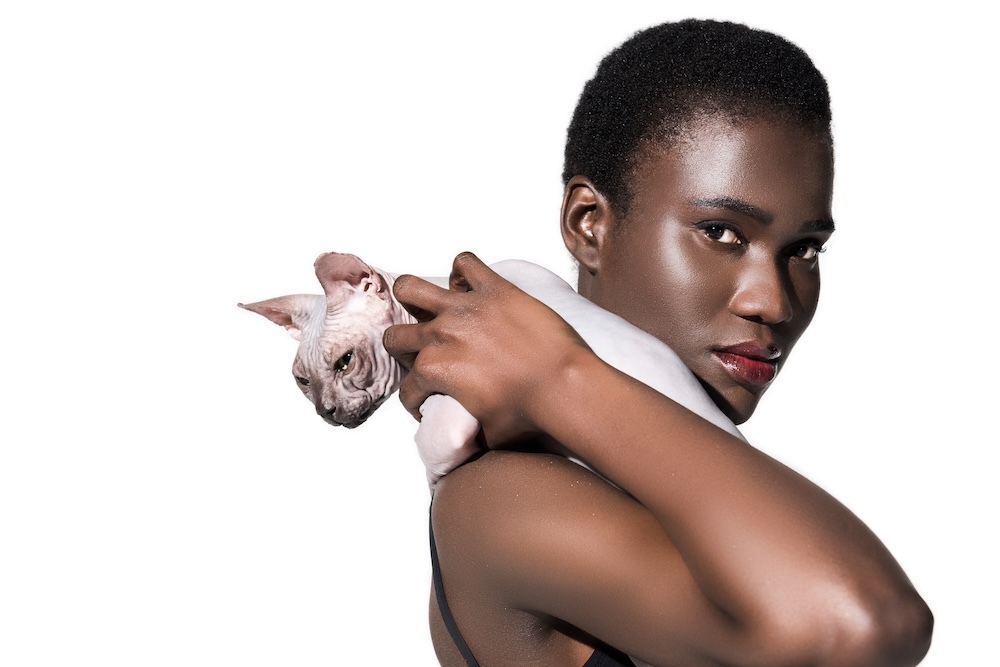 Woman holding a sphynx cat on her shoulder