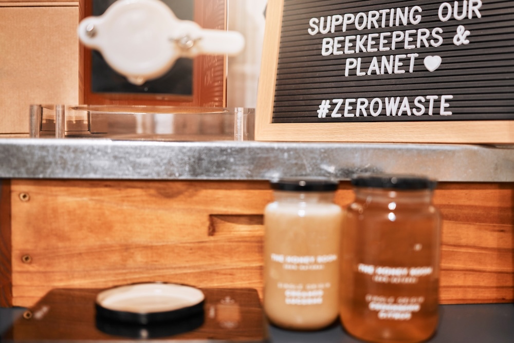 Honey in a glass jar with a sign that says supporting zero waste and the planet