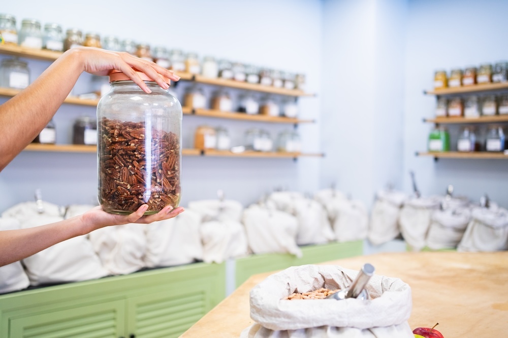 Zero waste Shopkeeper holding a glass jar of pecans