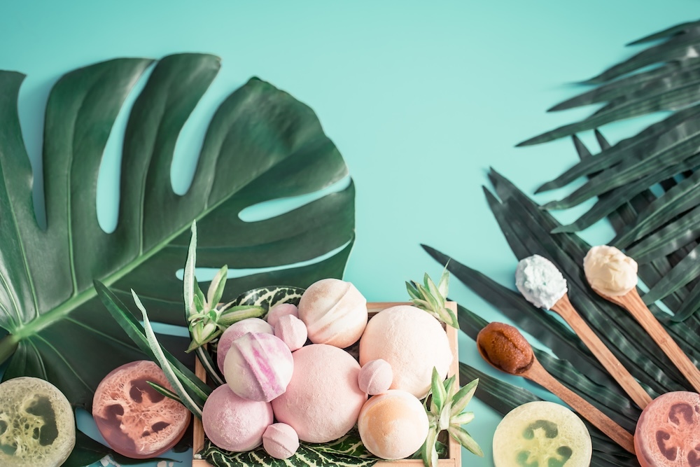 Beauty and bathroom products on the table with large plant leaves