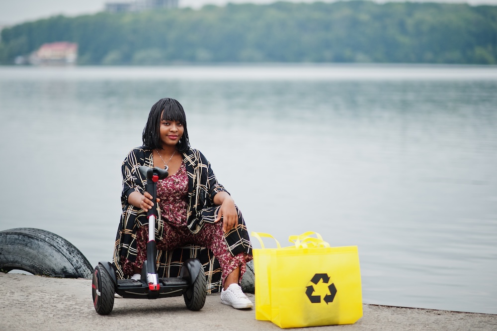 Young woman sitting next to her segway and reusable bag