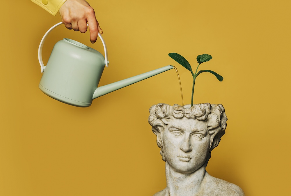 person watering statue of a stoic figure thats a planter