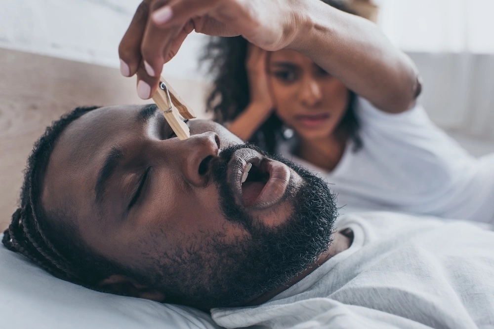 Up close of a man snoring with wife plugging nose