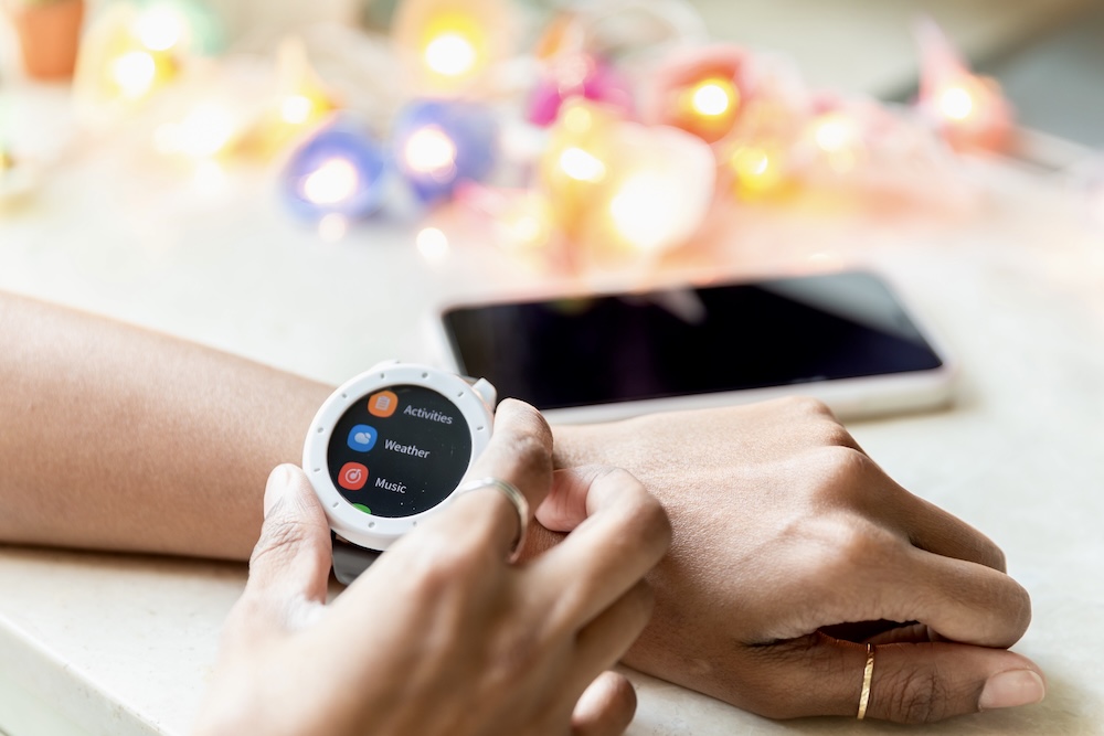 Person setting smartwatch with smartphone in background