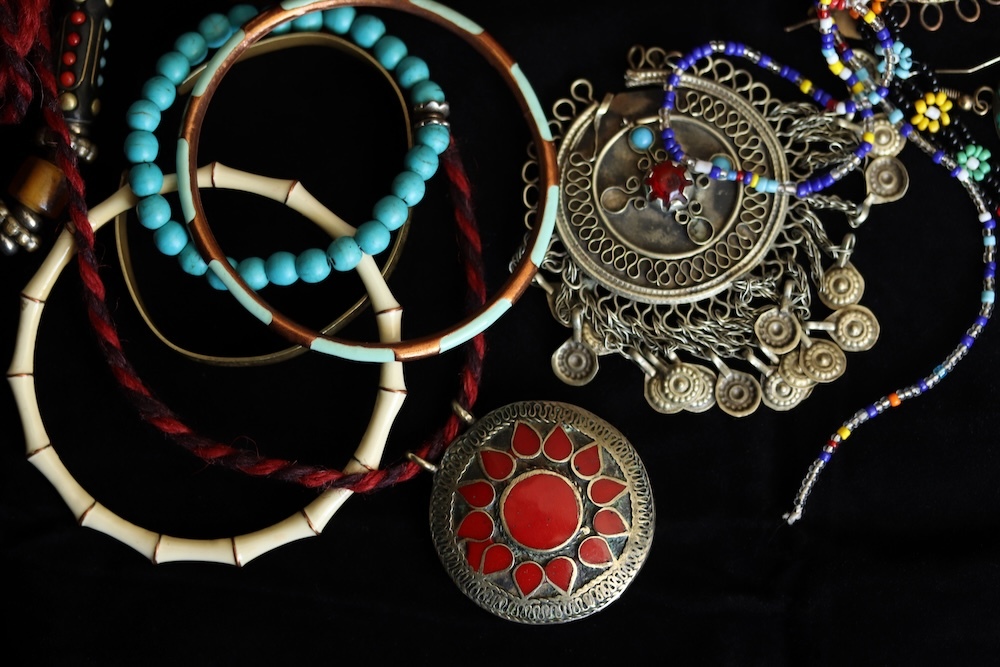 Various pieces of silver and bead jewelry on a black background