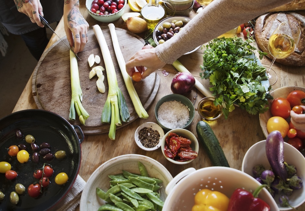 Couple preparing vegetarian meal on dinner table