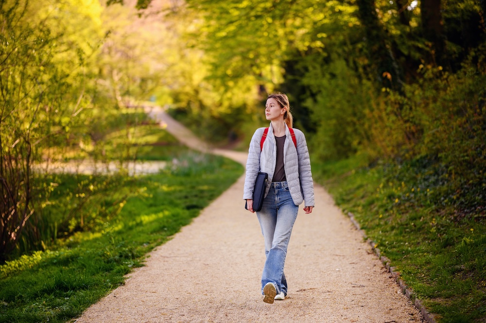 Young blonde woman walking alone on a path