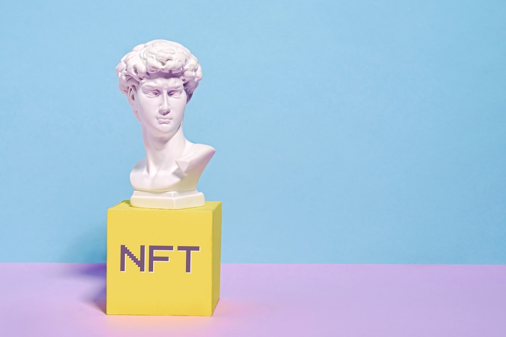 Status sitting on top of a block that spells NFT