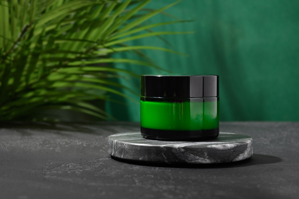 Green bottle of face cream with a plant