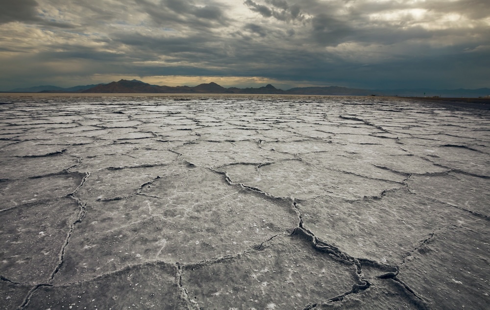 dried up cracked land with mountains in the distant background