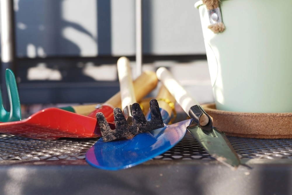 gardening tools on a table with pot and gloves