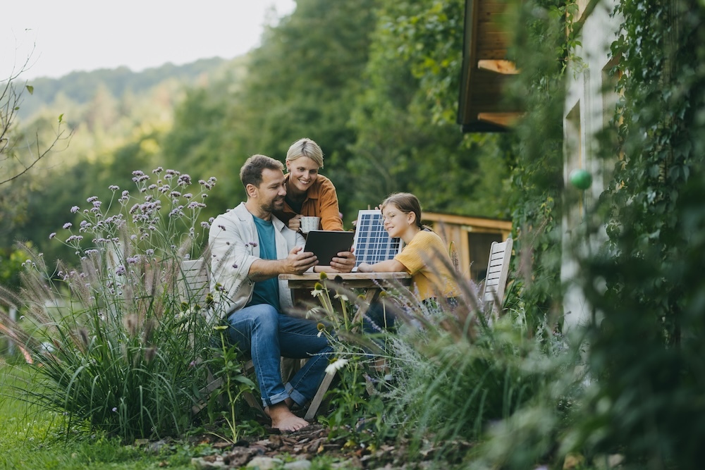 parents and daughter sitting outside using table top solar power panel