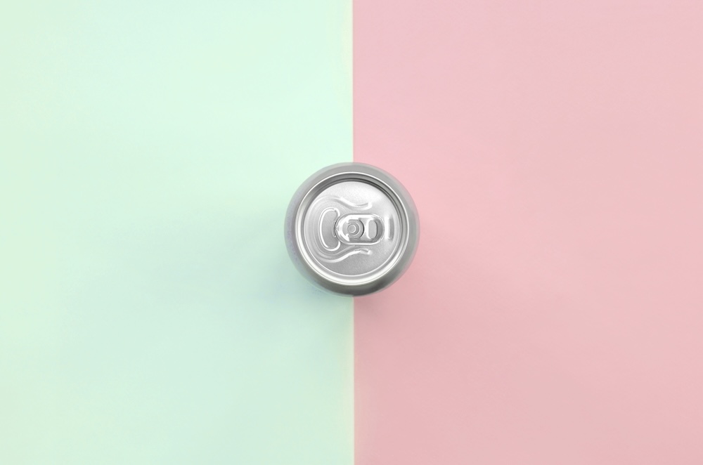Top of soda can with light green and pink background