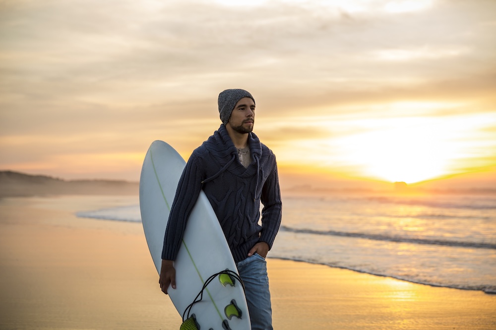 Man walking on beach with his surf board