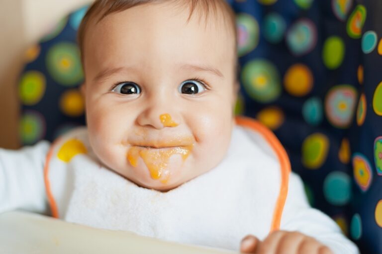 Happy baby with baby food on his chin