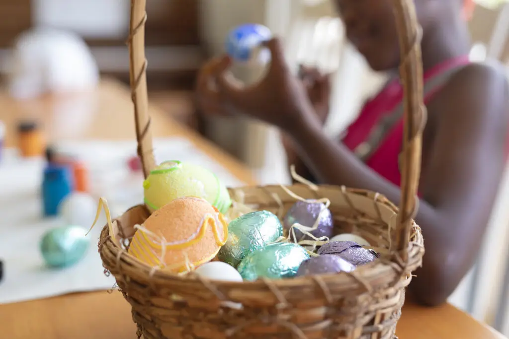 little girl decorating easter eggs with a basket