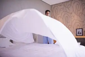 man making his bed fluffing bamboo sheets