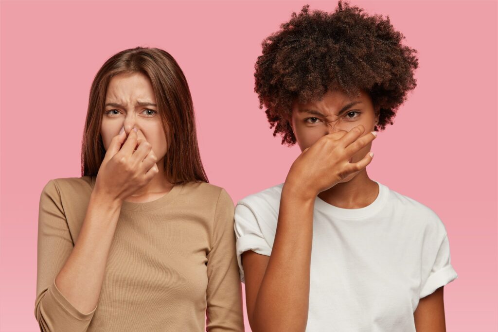 two women holding nose because of weird smell