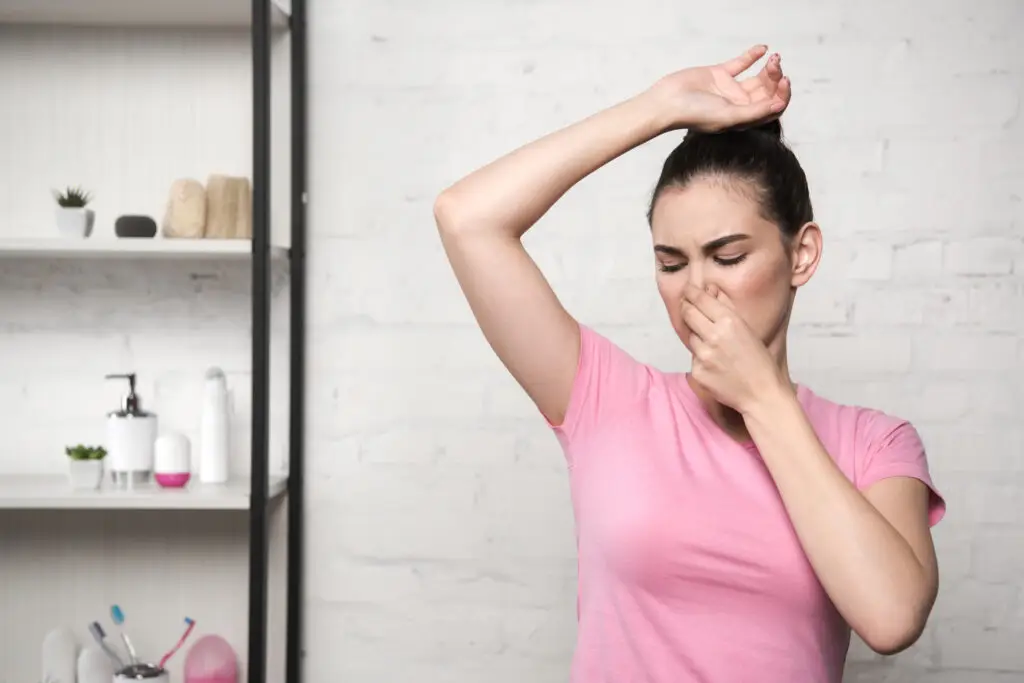 woman holding nose smelling bad body odor