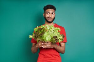 man holding lettuce confused about the meaning of vegan