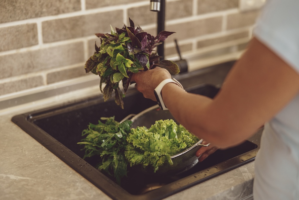 person rinsing off green vegetables