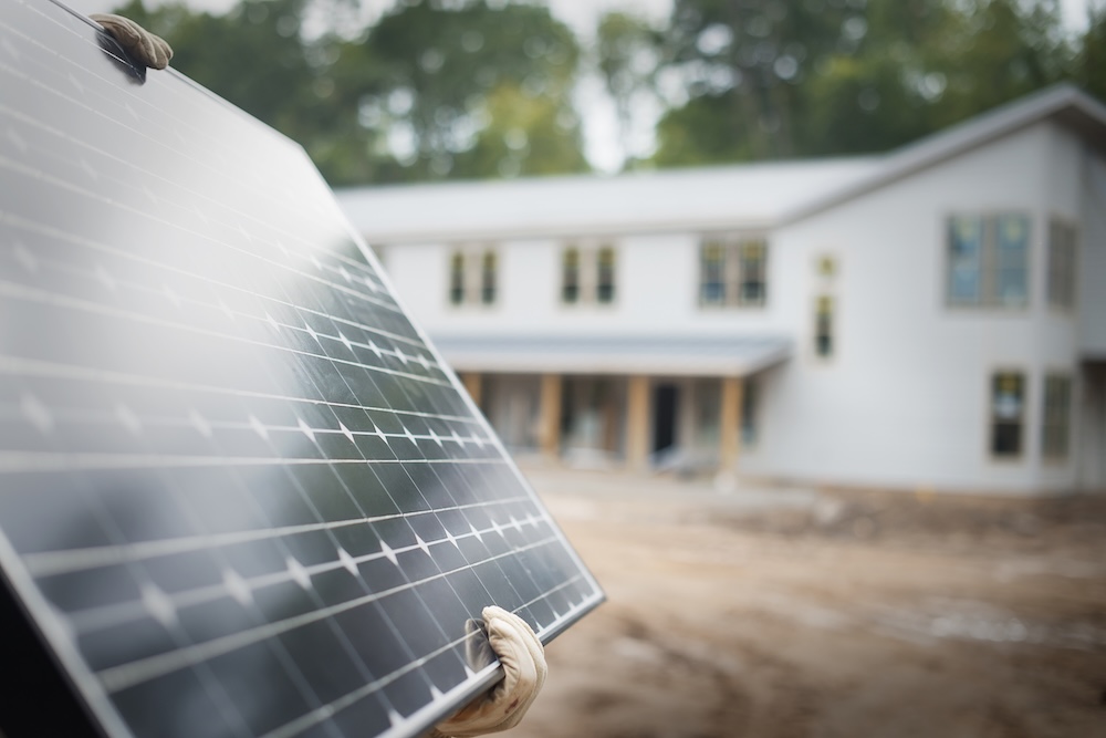 person carrying a solar panel to install on home