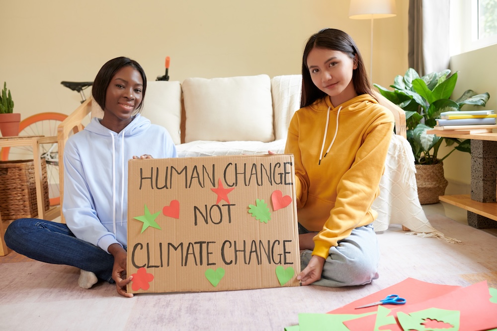 two women holding a sign that says human change not climate change