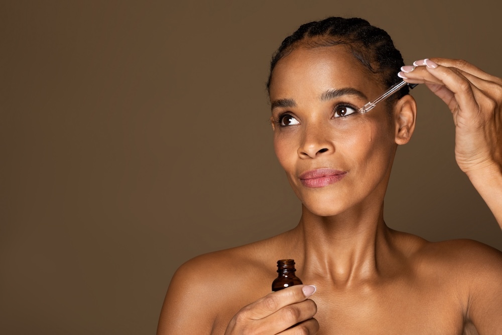 middle aged woman applying serum to eye area