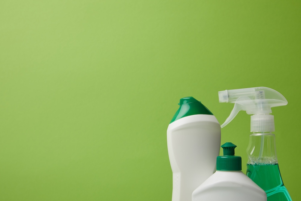 Cleaning supplies in plastic bottles on a green background