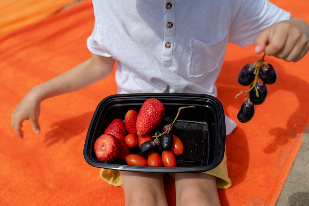 child eating fruit from a black plastic container