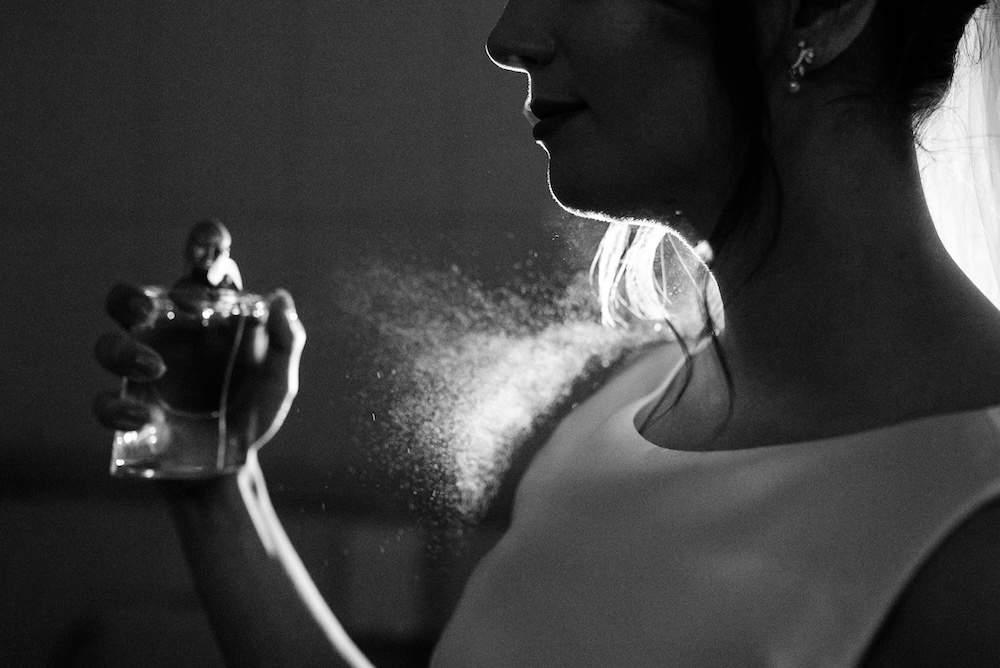 woman spraying perfume on herself and in the air