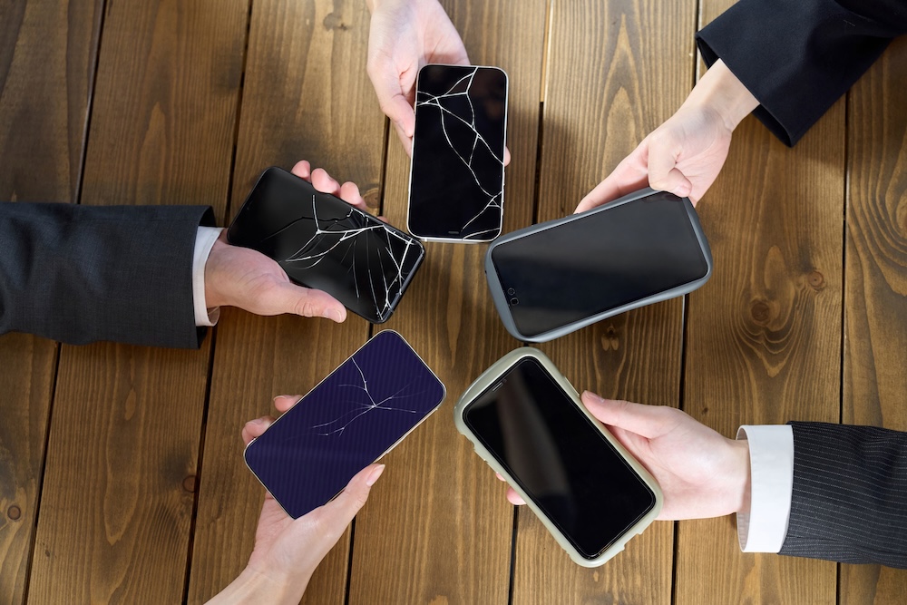 hands holding their broken smartphone screens