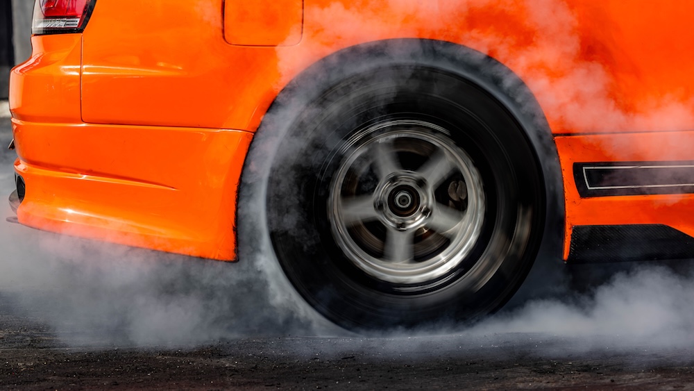 car burning out tires with white particles going in the air