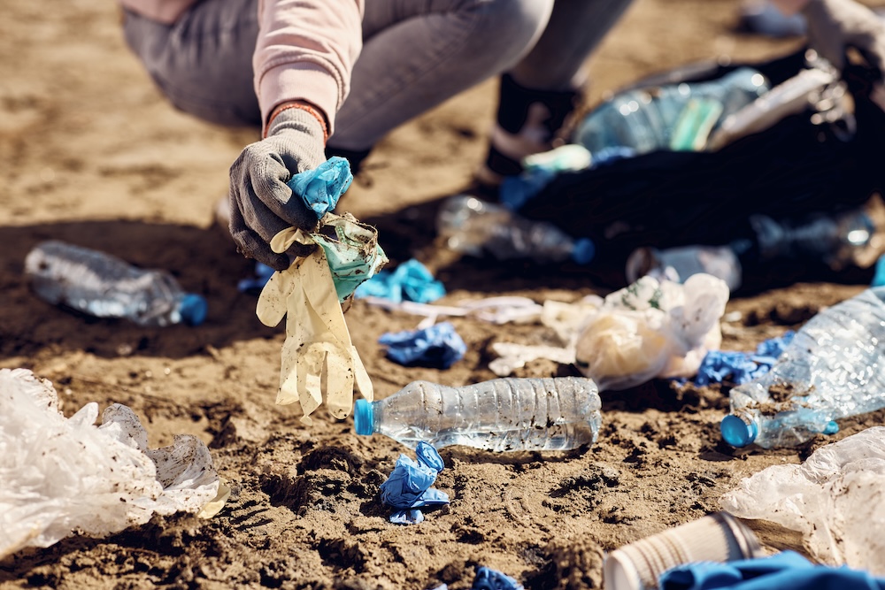 person picking up plastic on the beach