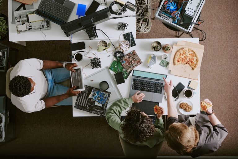 people working in a clutter workspace with multiple devices