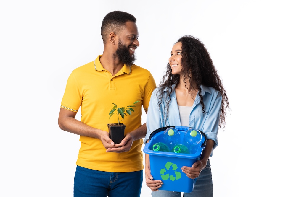 two people one person holding a plant and the other a recycling bin