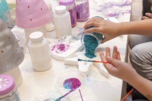 young child pouring out blue glitter on a table