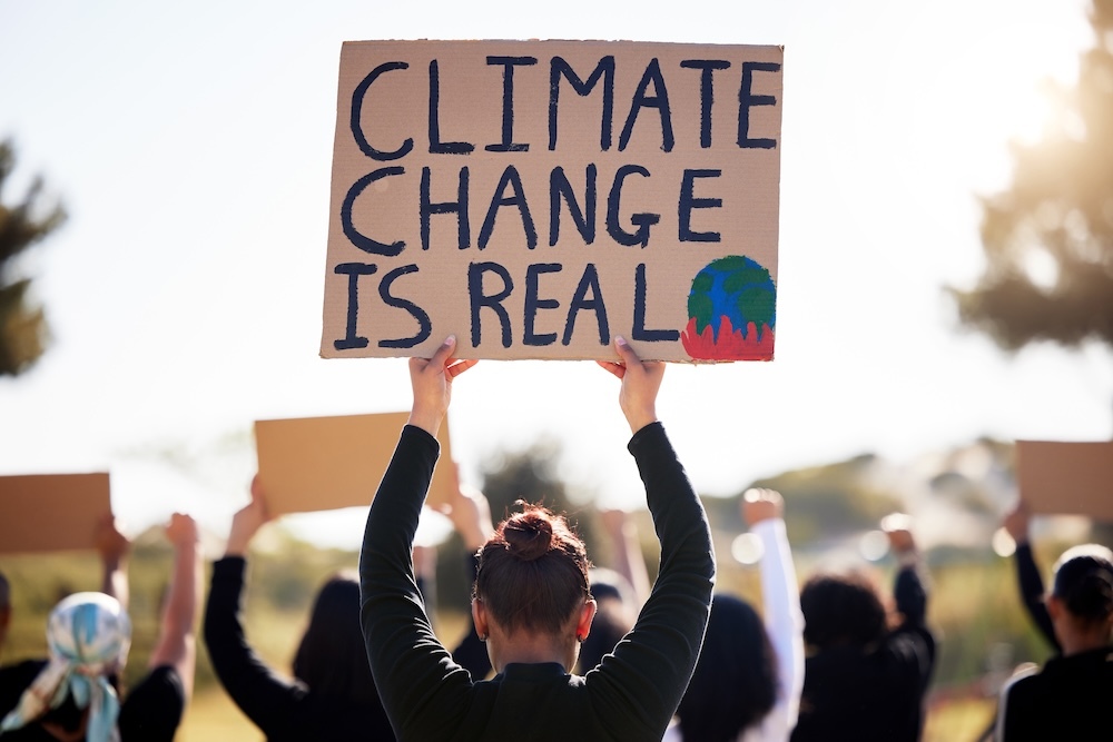 person holding a sign that says climate change is real