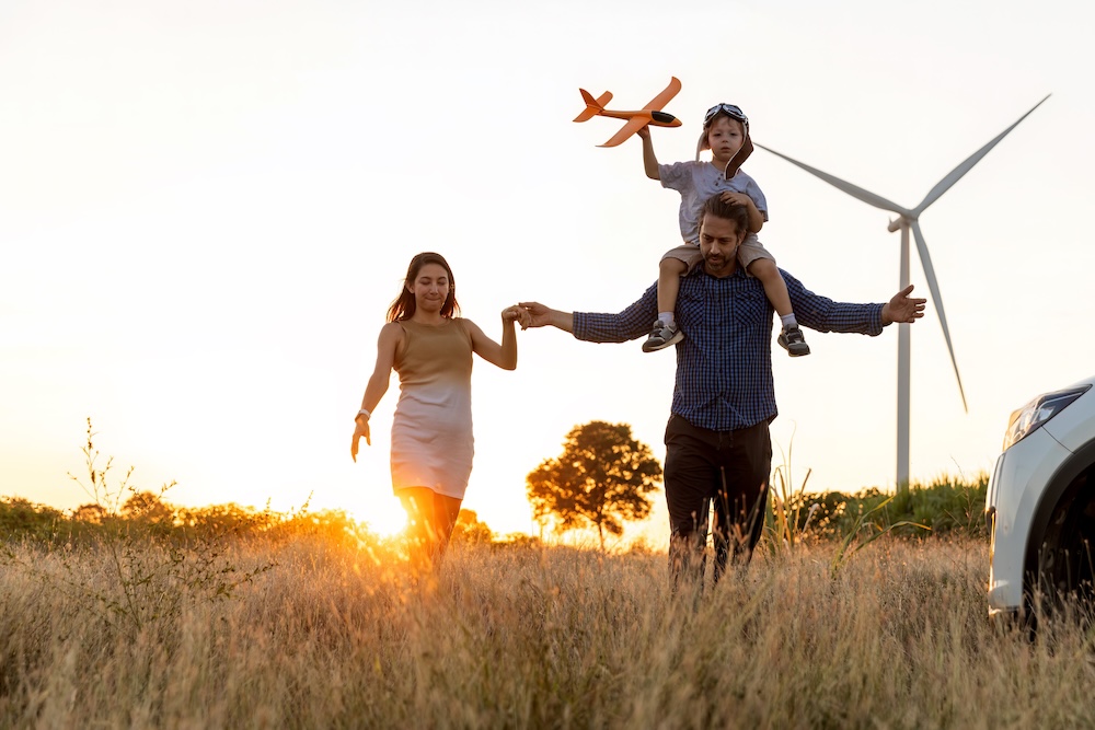 family walking in a field with a wind farm