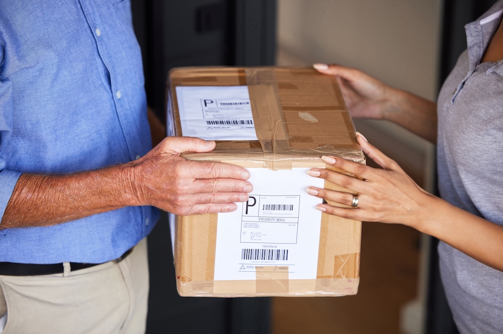 delivery man handing package to woman