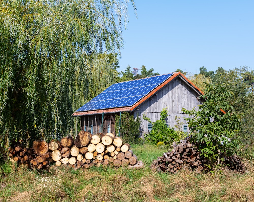 solar powered off-grid cabin with logs stacked outside