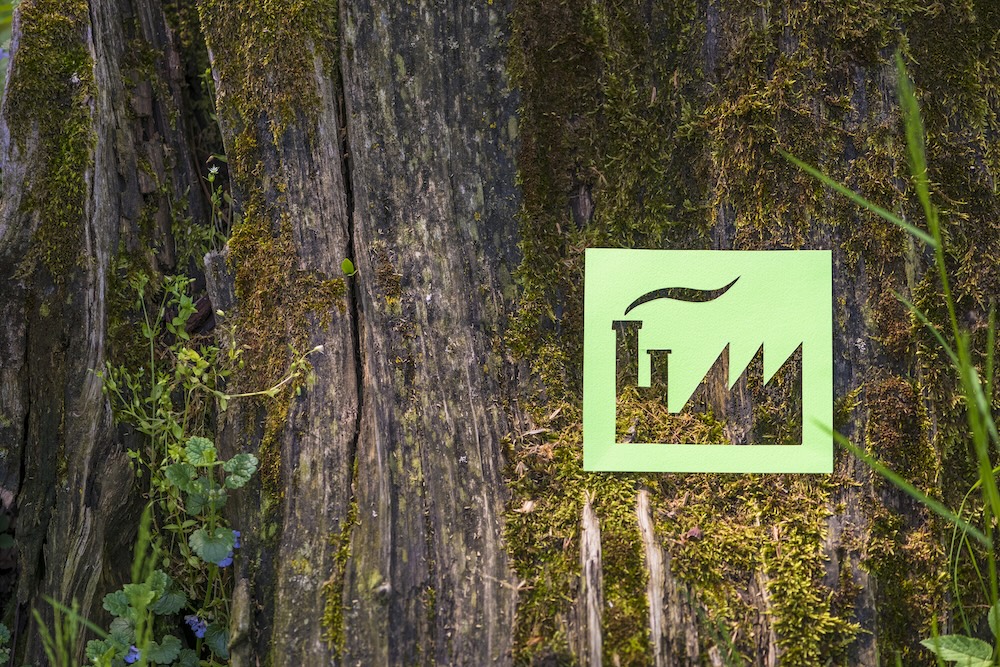 green paper cut out of a factory against a tree