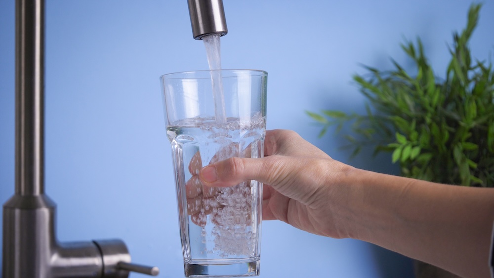 person filling up a glass with water