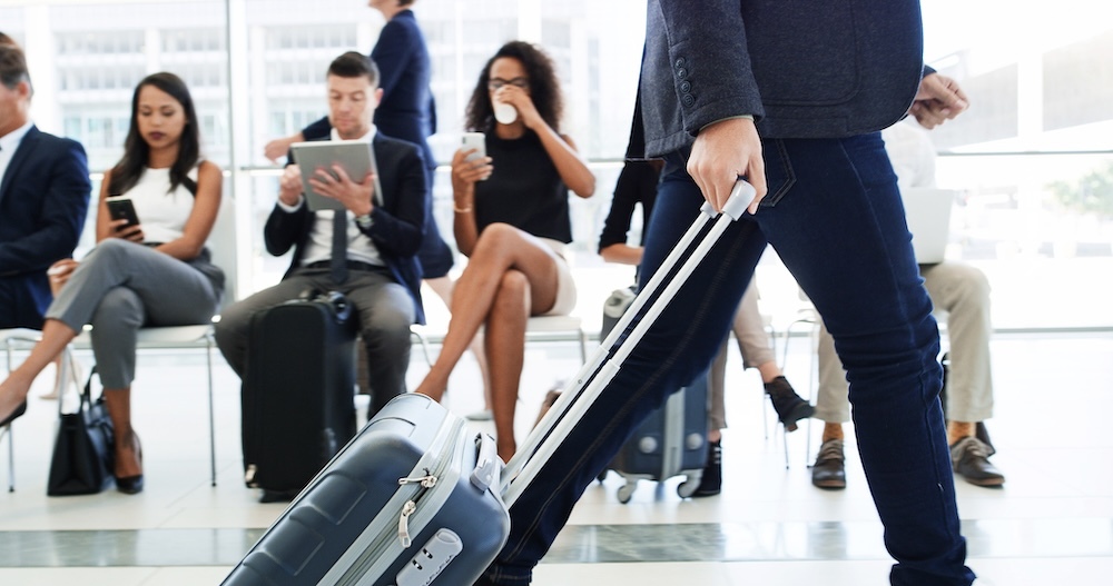 person walking with luggage passing other waiting airplane passengers