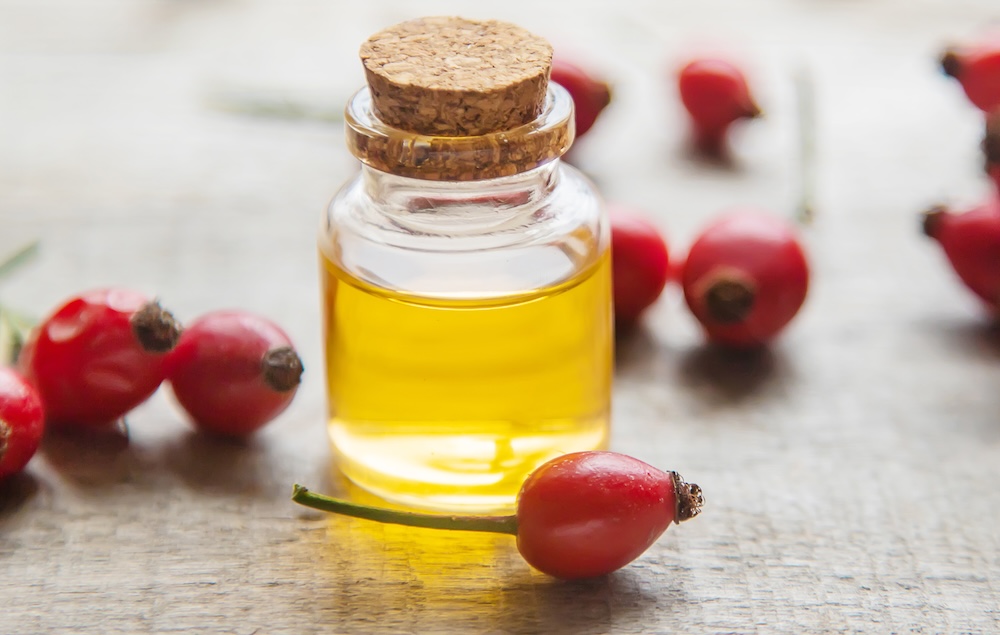 rose hip oil on a table with rose hip berries