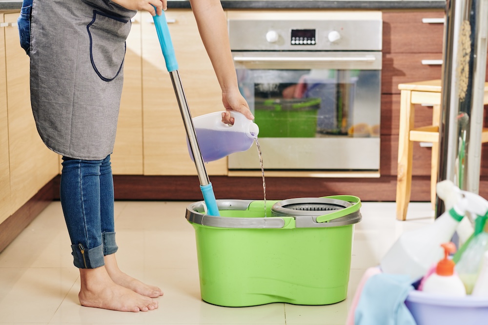 woman dipping mop in bucket with cleaner