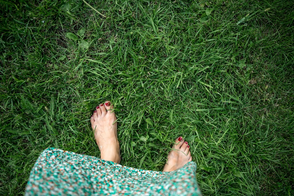 woman walking barefoot in the grass