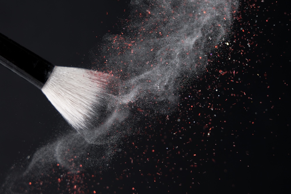 makeup brush with powder going into the air