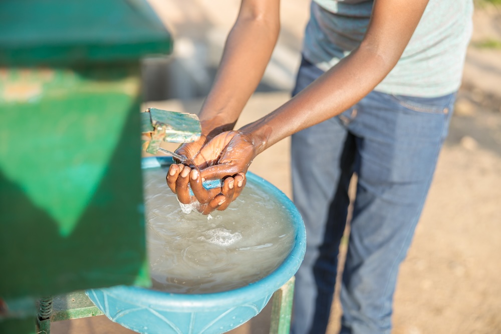 farm worker washing his hands from a water hose