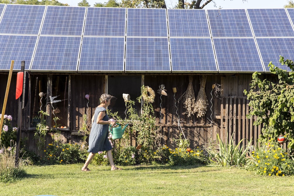 woman walking by her garden to her off-grid home